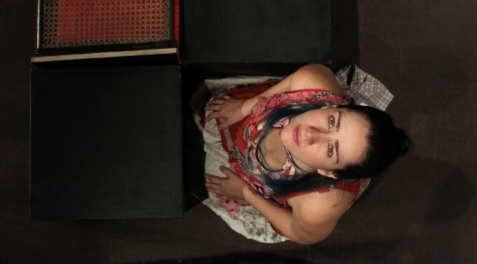 Jéssica Menkel, atriz loira de olhos verdes, agachada de joelhos, olha para o alto na peça Cálculo Ilógico em foto de Bia Chaves