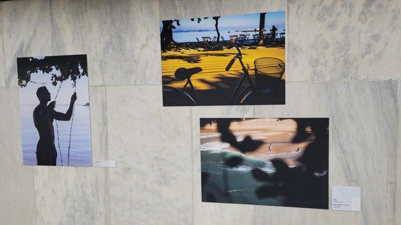 Três fotos em exposição no MetrôRio, estação Central. Na primeira, a silhueta de um homem, em outra uma bicicleta e na terceira, uma praia.