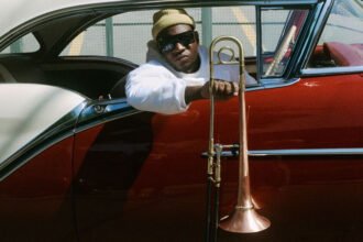 Joabe num carro vermelho segura seu instrumento musical