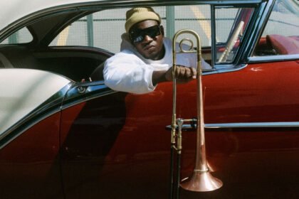 Joabe num carro vermelho segura seu instrumento musical