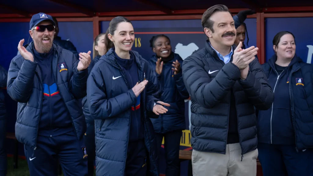 Brendan Hunt, Tanya Reynolds e Jason Sudeikis em “Ted Lasso”, já disponível no Apple TV.